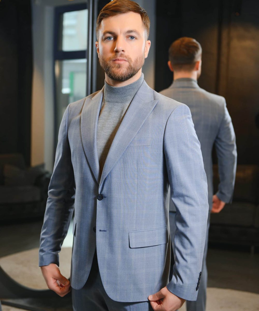 Smiling man trying on suit at mirror in menswear shop.